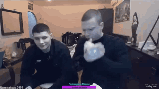 two men are sitting in front of a screen that says 5000 on the bottom right