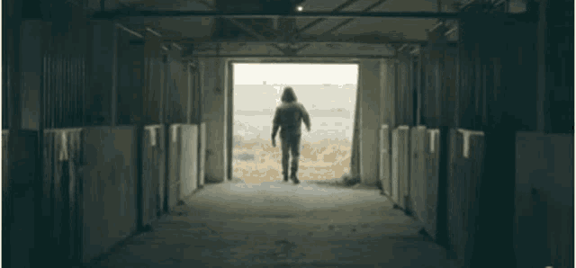 a row of horse stables with the door open to a field