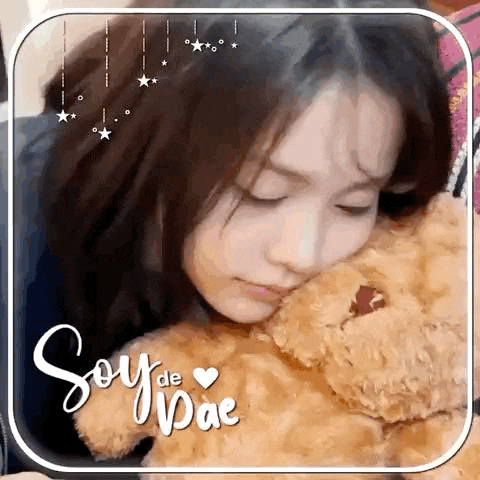 a woman is holding a teddy bear in her arms and looking at it .