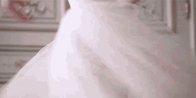 a woman in a pink dress is dancing in a room in front of a dresser .