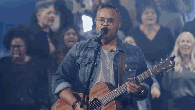 a man is singing into a microphone while holding a guitar
