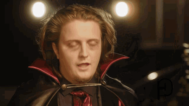 a man dressed as a vampire with a red cape and tie