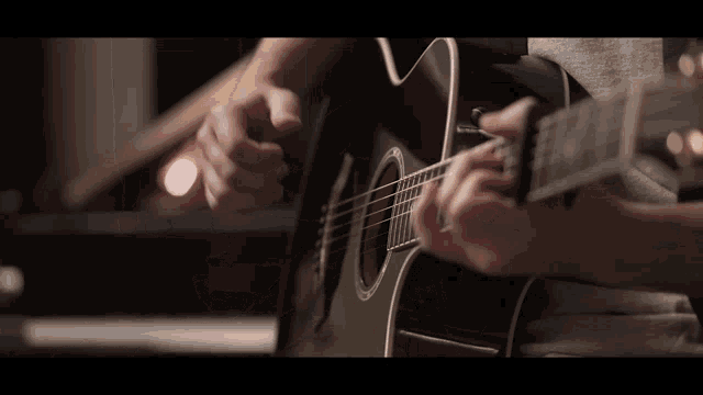 a person is playing an acoustic guitar with a gray shirt on