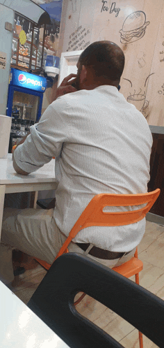 a man sits in front of a pepsi fridge