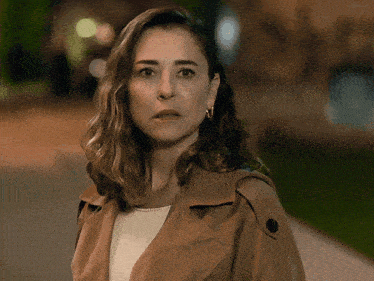 a woman wearing a brown trench coat and hoop earrings