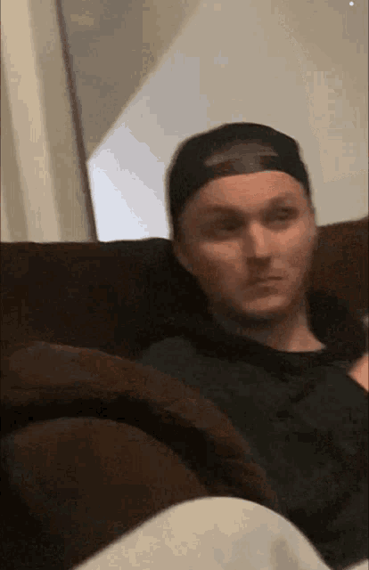a man wearing a hat is sitting on a couch