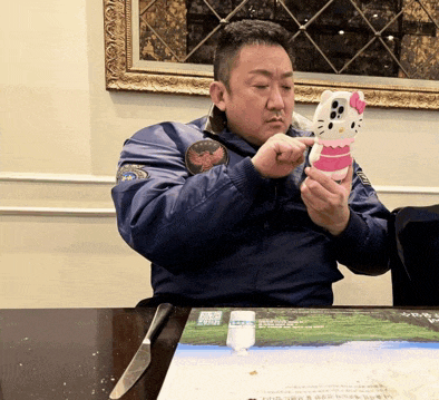 a man sitting at a table holding a hello kitty case