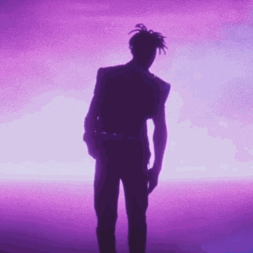 a silhouette of a man standing in front of a purple background with his hands in his pockets .
