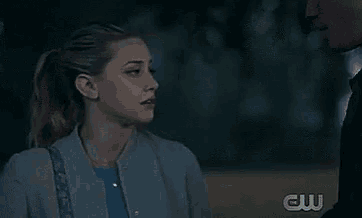 a woman in a ponytail is standing in a field at night and looking at the camera .