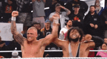 two men in a wrestling ring with a crowd behind them and a sign that says cw
