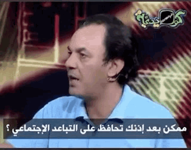 a man in a blue shirt is talking on a television show in arabic .