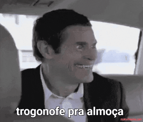 a man in a suit and white shirt is smiling and says " trogonofe pra almoça " .