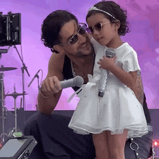 a little girl is holding a microphone next to a man .