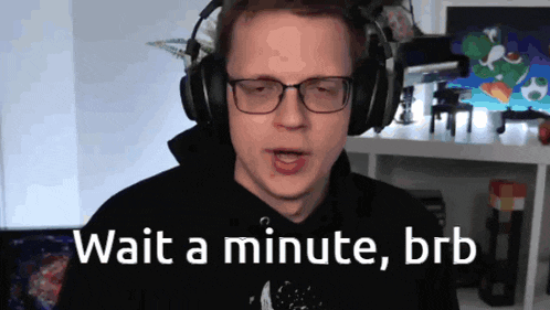 a man wearing headphones and glasses says " wait a minute brb "