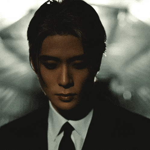 a man in a suit and tie is looking down at something