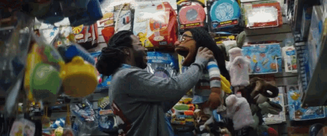 a man holds a stuffed animal in front of a display of toys