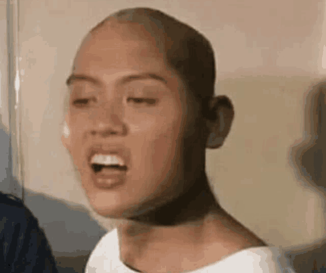 a man with a bald head is making a funny face with his mouth open .
