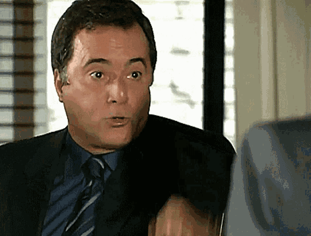 a man in a suit and tie looks surprised