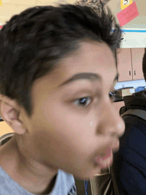 a close up of a young boy 's face with a note on the ceiling that says " doesn 't know "