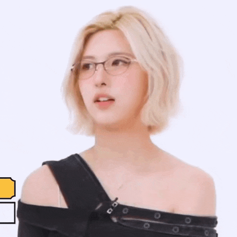 a woman wearing glasses and a black off the shoulder top is looking at the camera .