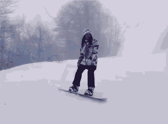 a woman is riding a snowboard on a snowy hill