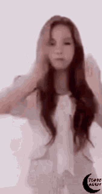 a woman with long hair is standing in front of a white background and holding her hair .