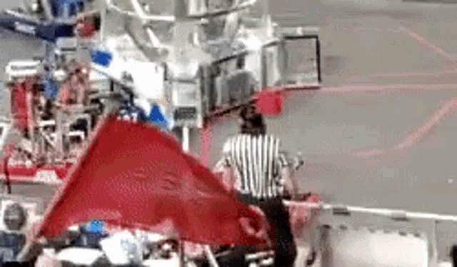 a referee is holding a red flag in front of a group of people .