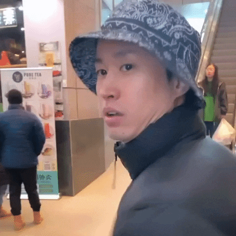 a man wearing a hat in front of a pure tea sign