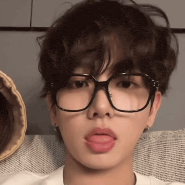 a young man wearing glasses sticks out his tongue