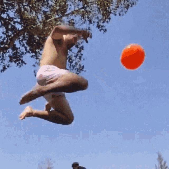 a shirtless man is jumping in the air with an orange ball