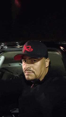 a man wearing a black hat with a red r on it