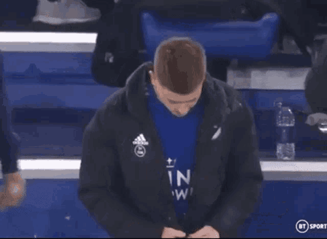 a man wearing a black jacket and a blue shirt that says in on it