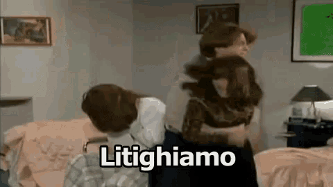 a man and a woman are fighting in a living room and the words litighiamo are visible .