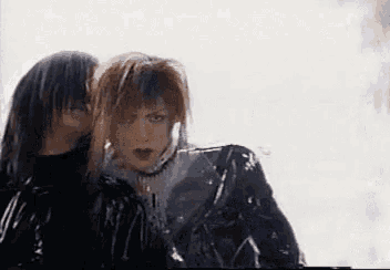 a couple of people are standing next to each other and one of them is wearing a black jacket .