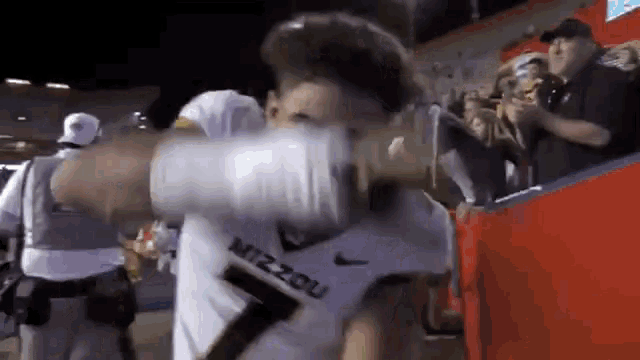 a man wearing a mizzou jersey is holding a glove in his hand