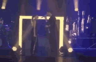 a man and a woman are singing into microphones on a stage in front of a crowd .