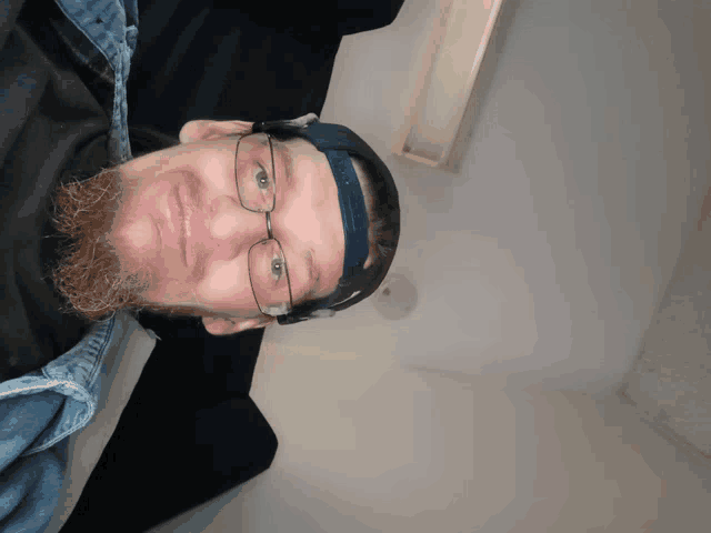 a man wearing glasses and a hat is laying on a couch