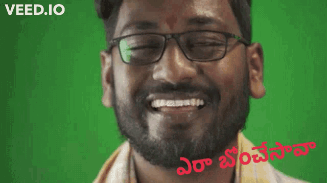 a man with glasses and a beard is smiling in front of a green screen that says veed.io on it