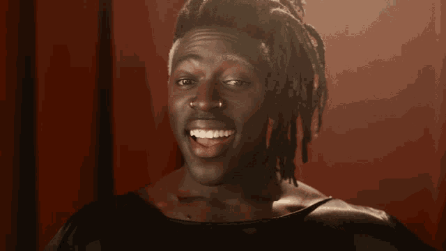 a man with dreadlocks is smiling and wearing a black shirt