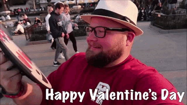 a man wearing glasses and a hat holds a sign that says happy valentine 's day