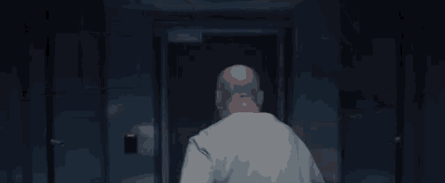 a bald man in a white shirt is walking through a doorway .