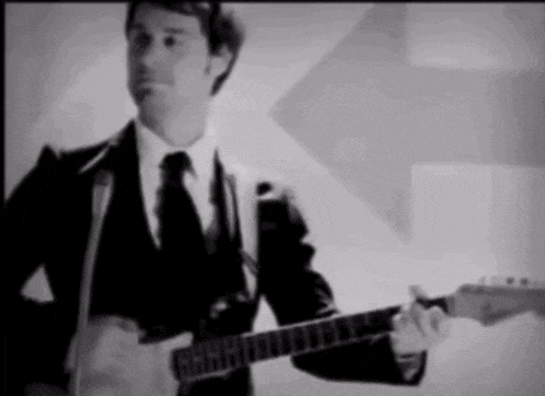 a man in a suit is playing a guitar