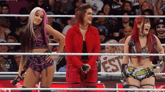 three women in a wrestling ring with a sign that says est on it