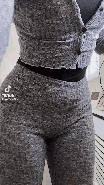 a woman is standing in a kitchen wearing a sweater and leggings .