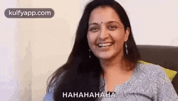 a woman is smiling while sitting on a couch and laughing .
