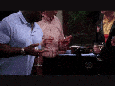 a group of men are standing around a table with wine glasses