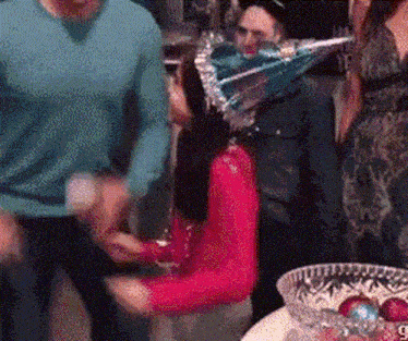 a woman wearing a party hat is sitting at a table with other people at a party .