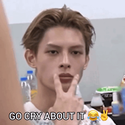 a young man is making a peace sign with the words go cry about it below him