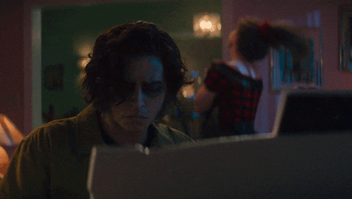 a man sitting at a desk with his eyes closed looking at a laptop
