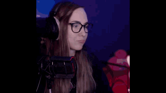 a woman wearing glasses and headphones is smiling and waving in front of a microphone with the words comoa in yellow letters